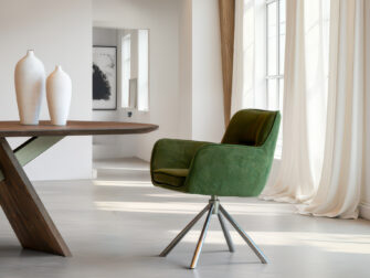 Fluwelen eetkamerstoel in bosgroen met een wit metalen kruispootonderstel