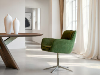 Groene eetkamerstoel met een strak, kruisvormig onderstel in geborsteld staal