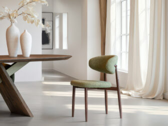 Minimalistische eetkamerstoel met walnootkleurige houten poten en fluweelgroene stoffering voor een natuurlijke uitstraling