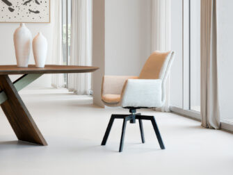 Modern vormgegeven stoel in beige-wit met brede zitting en robuuste zwarte pootconstructie