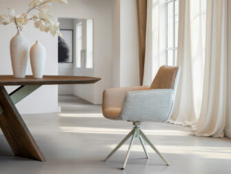 Gestoffeerde kuipstoel in beige met zwart metalen poten in kruisvorm