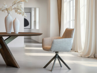 Zandkleurige kuipstoel met lichte textuur en industriële metalen basis