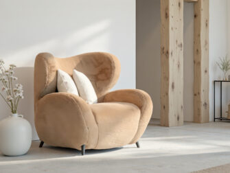 Fauteuil in zandkleurige stof met afgeronde vormen en diepe zit