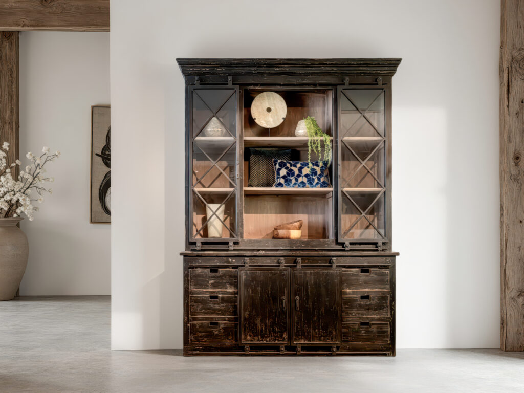 Zwarte houten vitrinekast met rustieke uitstraling en decoratieve elementen in het open middenvak