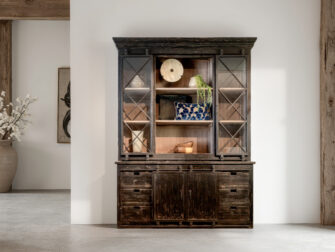 Zwarte houten vitrinekast met rustieke uitstraling en decoratieve elementen in het open middenvak