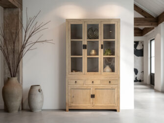 Licht houten vitrinekast met glazen deuren en landelijke uitstraling
