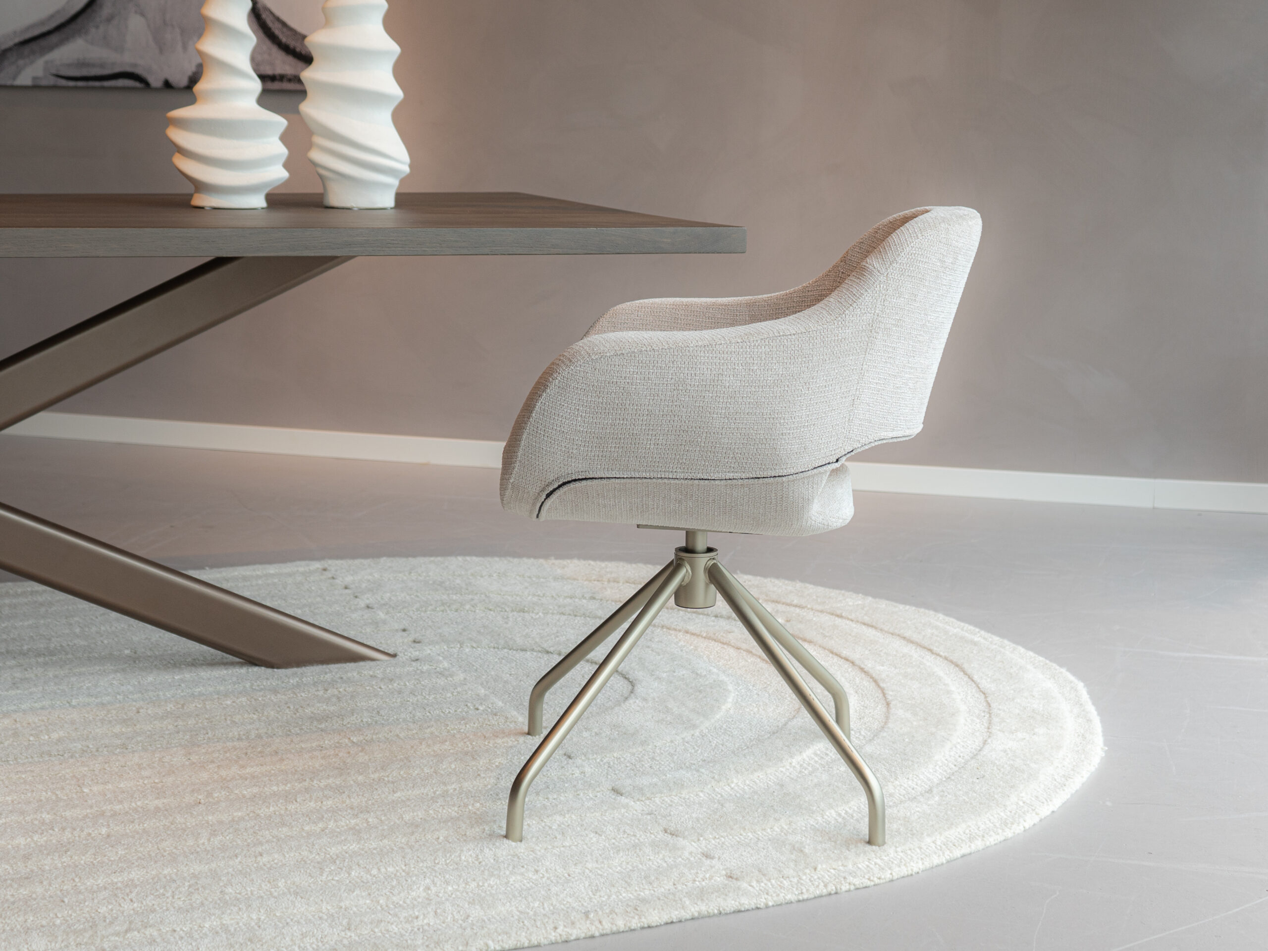 Beige kuipstoel met ronde vorm en champagne draaipoot