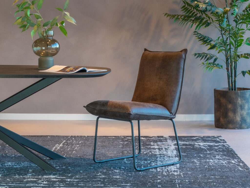 Stoere bruine leren eetkamerstoel met een zwarte beugelpoot