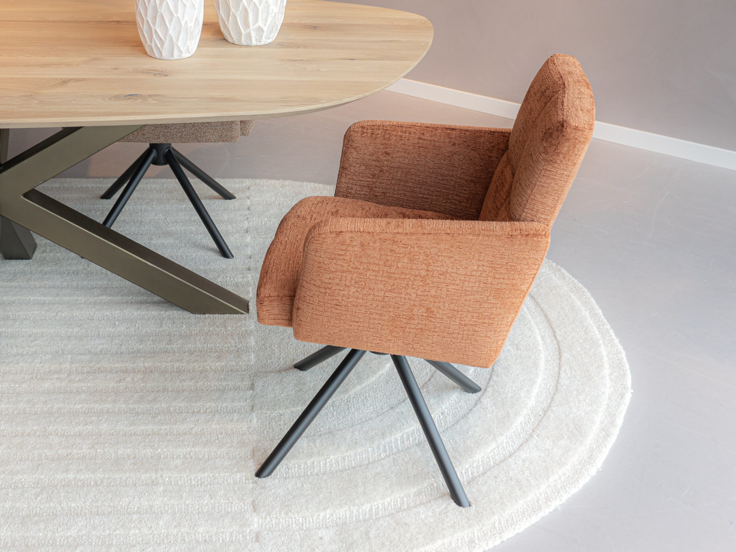 Luxe eetkamerstoel in koperkleurige zachte stof met armleuningen en een zwarte draaipoot