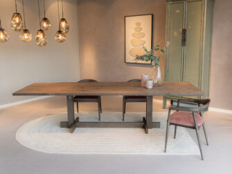 designstoel met halfronde rugleuning, donkerhouten frame en luxe roze bekleding