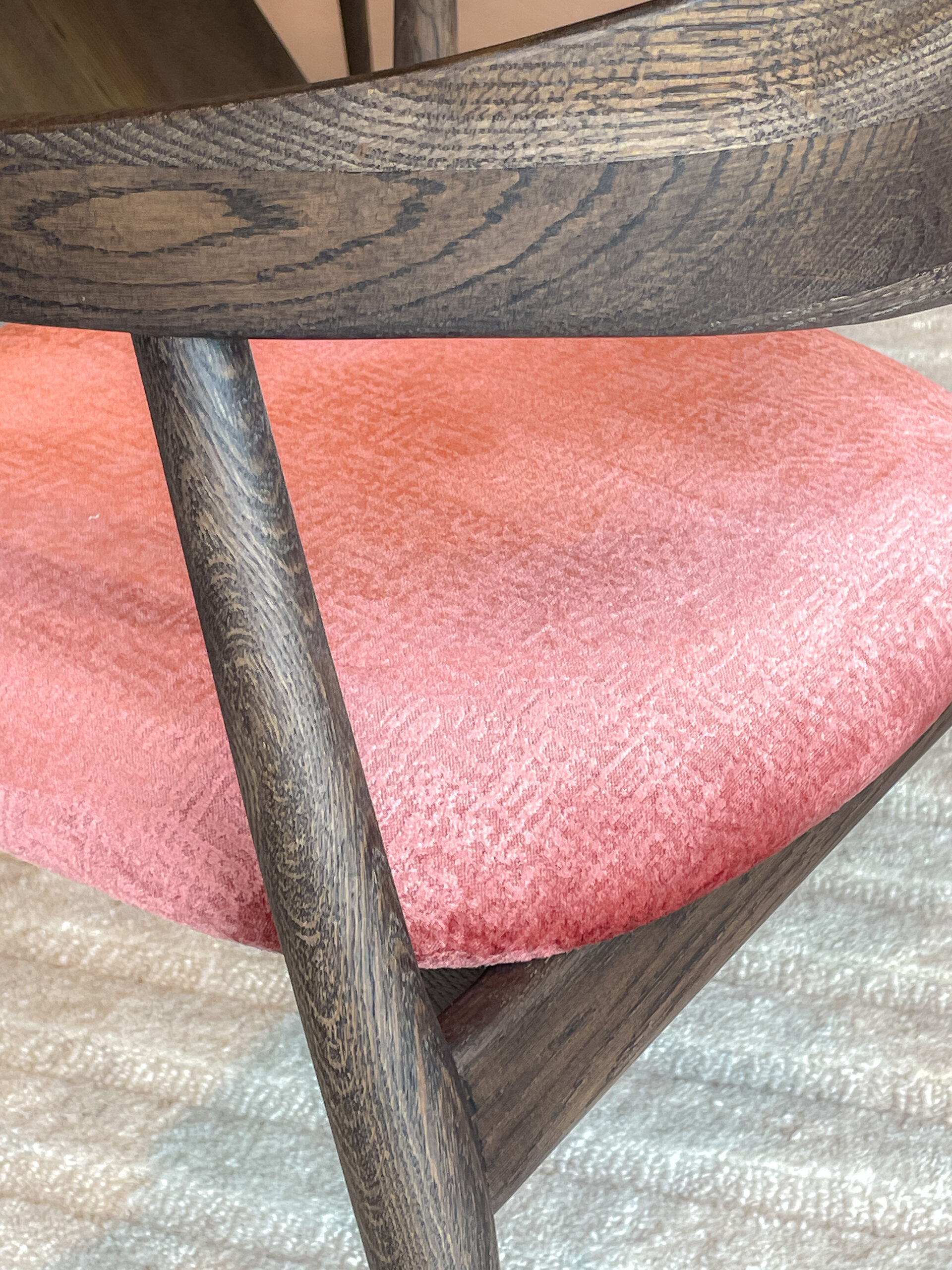 stevige houten stoel met ergonomisch gevormde open rugleuning en zachte roze zitting.