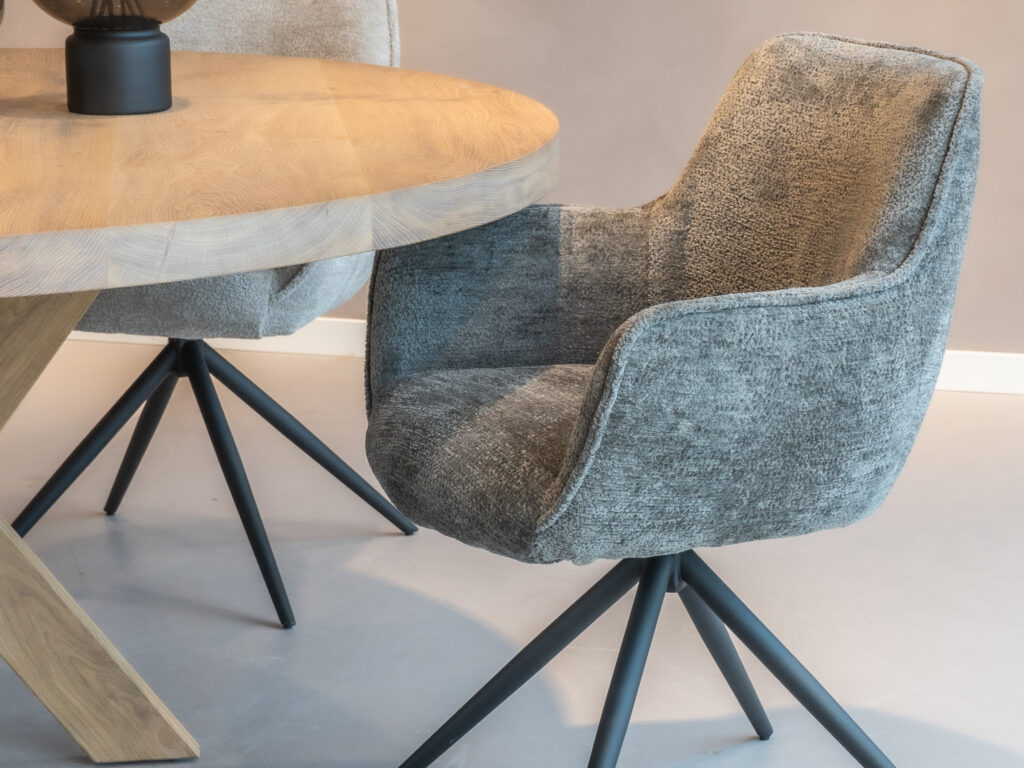 Grijze eetkamerstoel met een eigentijds ontwerp en zwarte poten.