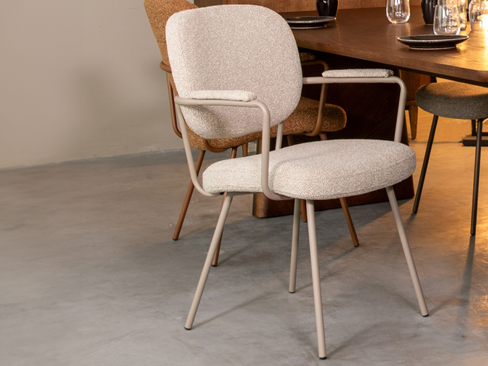 Stoel met zachte tinten en armleuningen, met licht metalen onderstel en comfortabele zitting