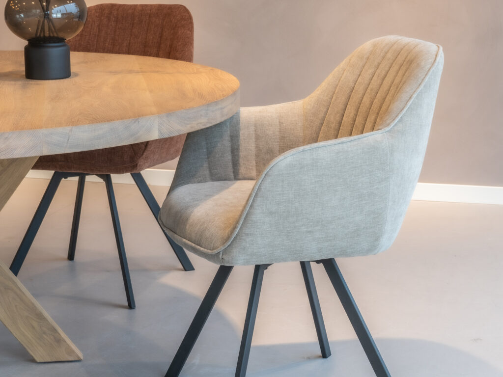 Beige-grijze eetkamerstoel met een modern design en zwarte poten.
