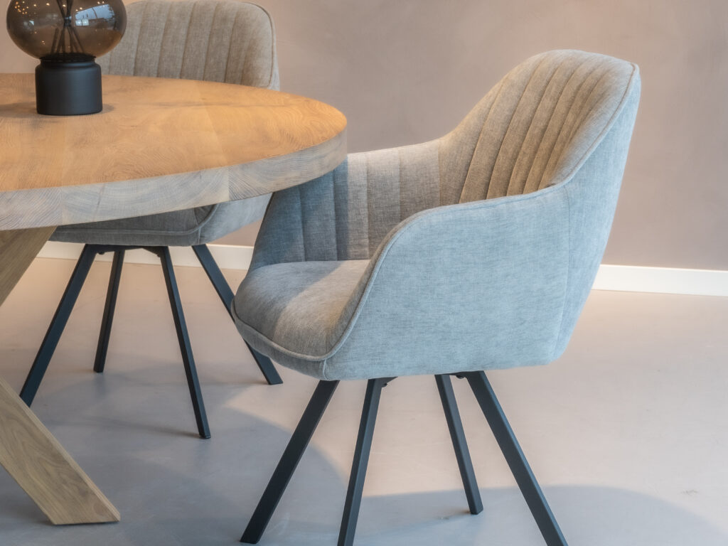 Blauwgrijze eetkamerstoel met een stijlvol ontwerp en zwarte poten.