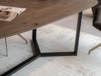 deze eiken eettafel valt op door zijn vorm en verfijnde stalen onderstel
