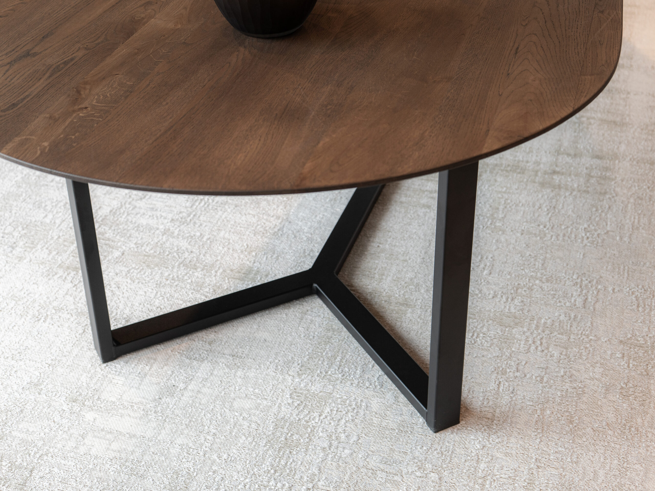 Organisch gevormde tafel van massief eiken met een strak en licht ogend onderstel in staal